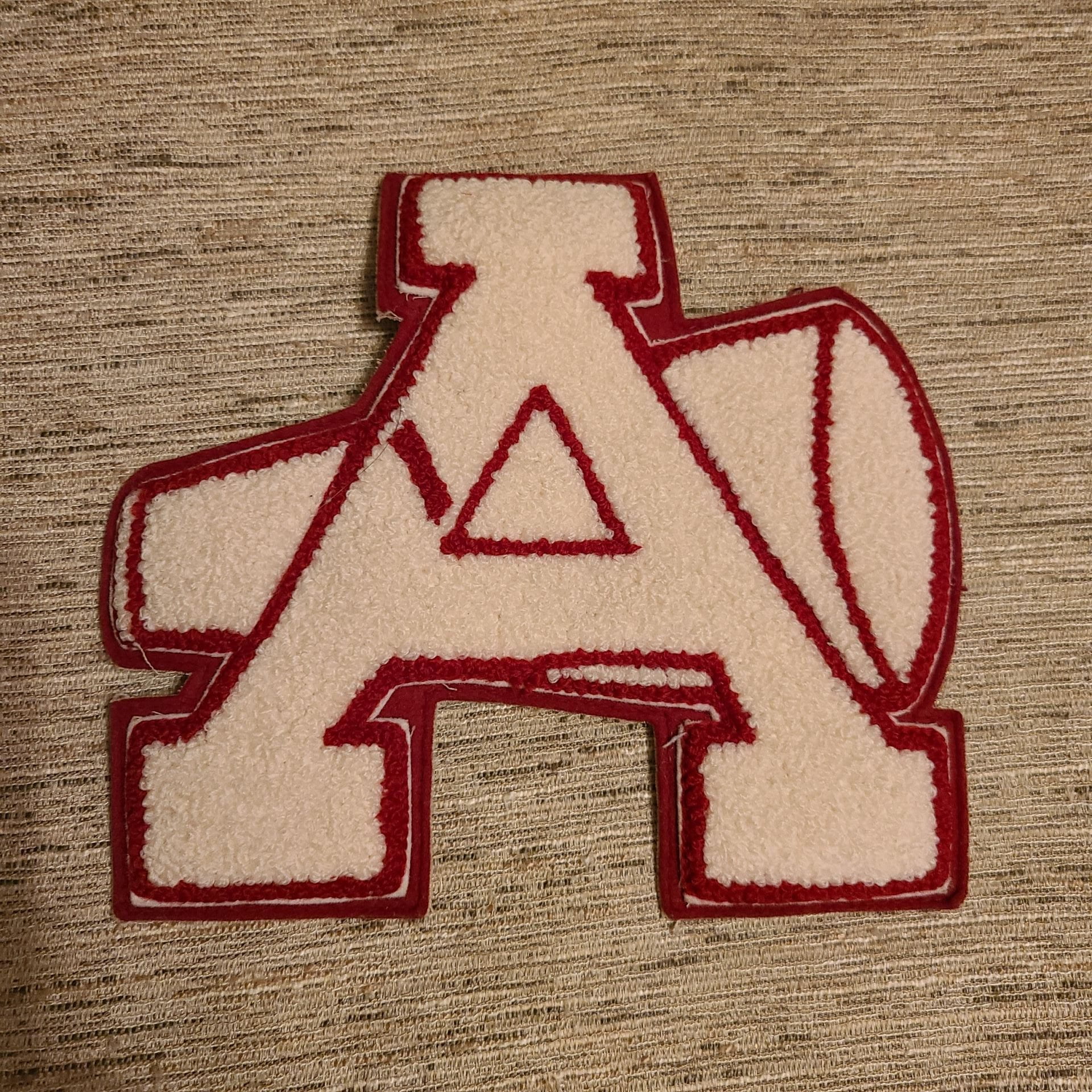 A white cheerleading letter "A" with a cheer horn behind it. The letter is outlined in red.