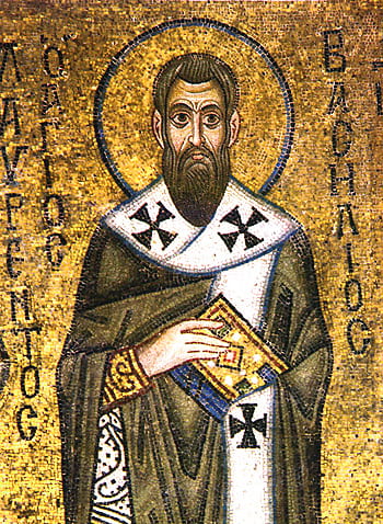 A tiled mosaic with a bright gold background a man in dark robes lined in white at the center. He is holding a book and has a blue circle surrounding his head.
