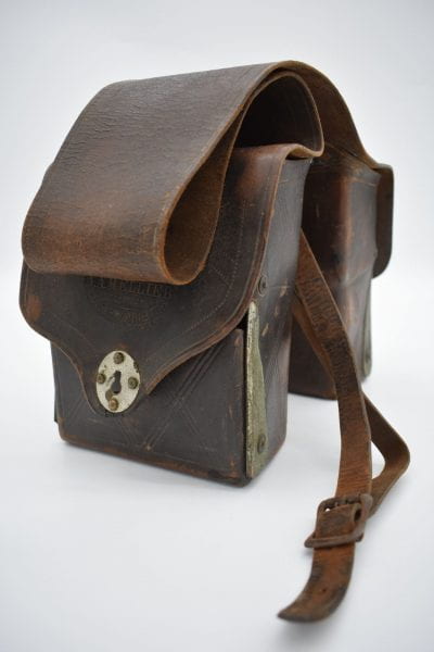 Two dark brown bags attached with a long strip of leather.
