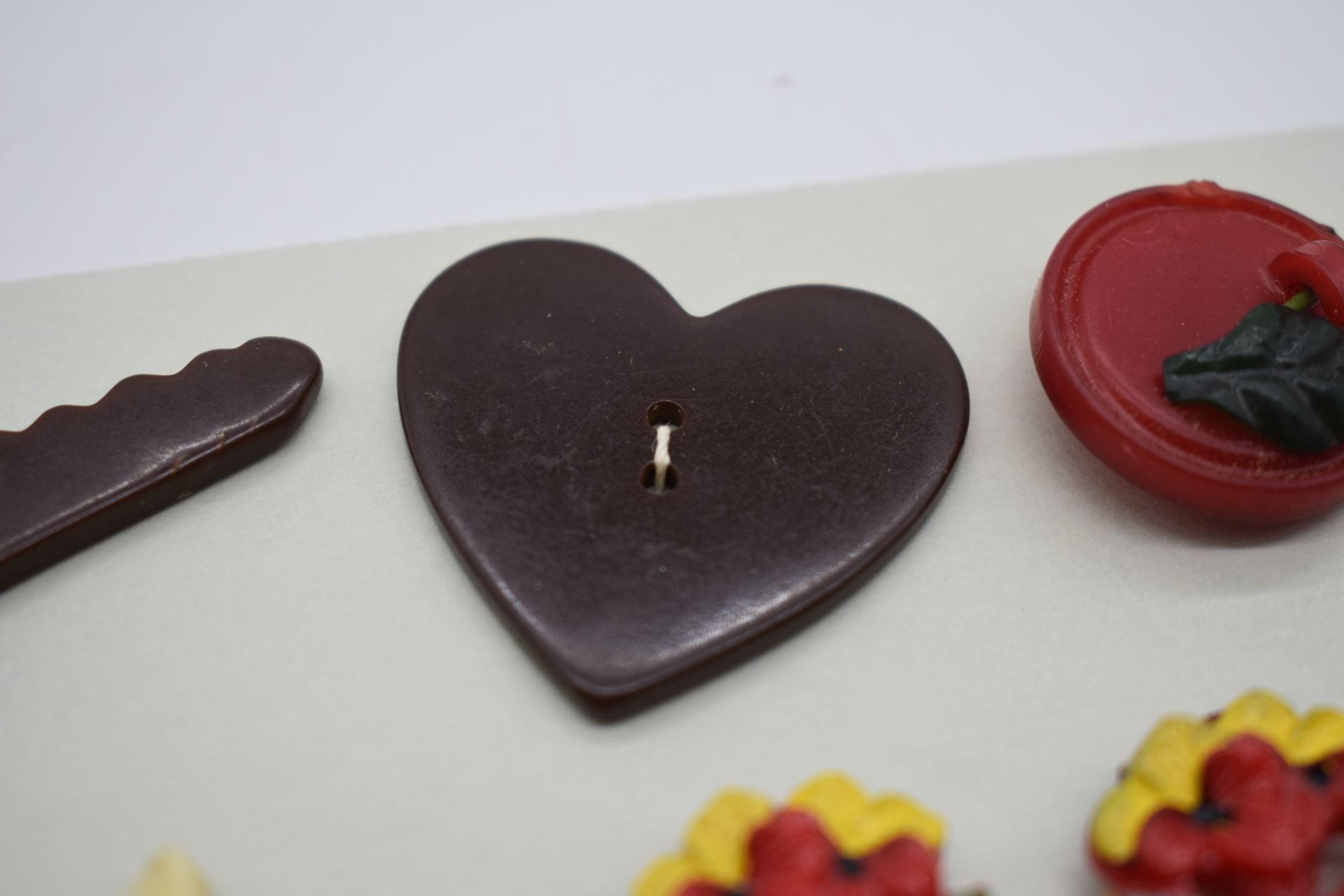 A large brown heart button sewn onto a slip of paper.