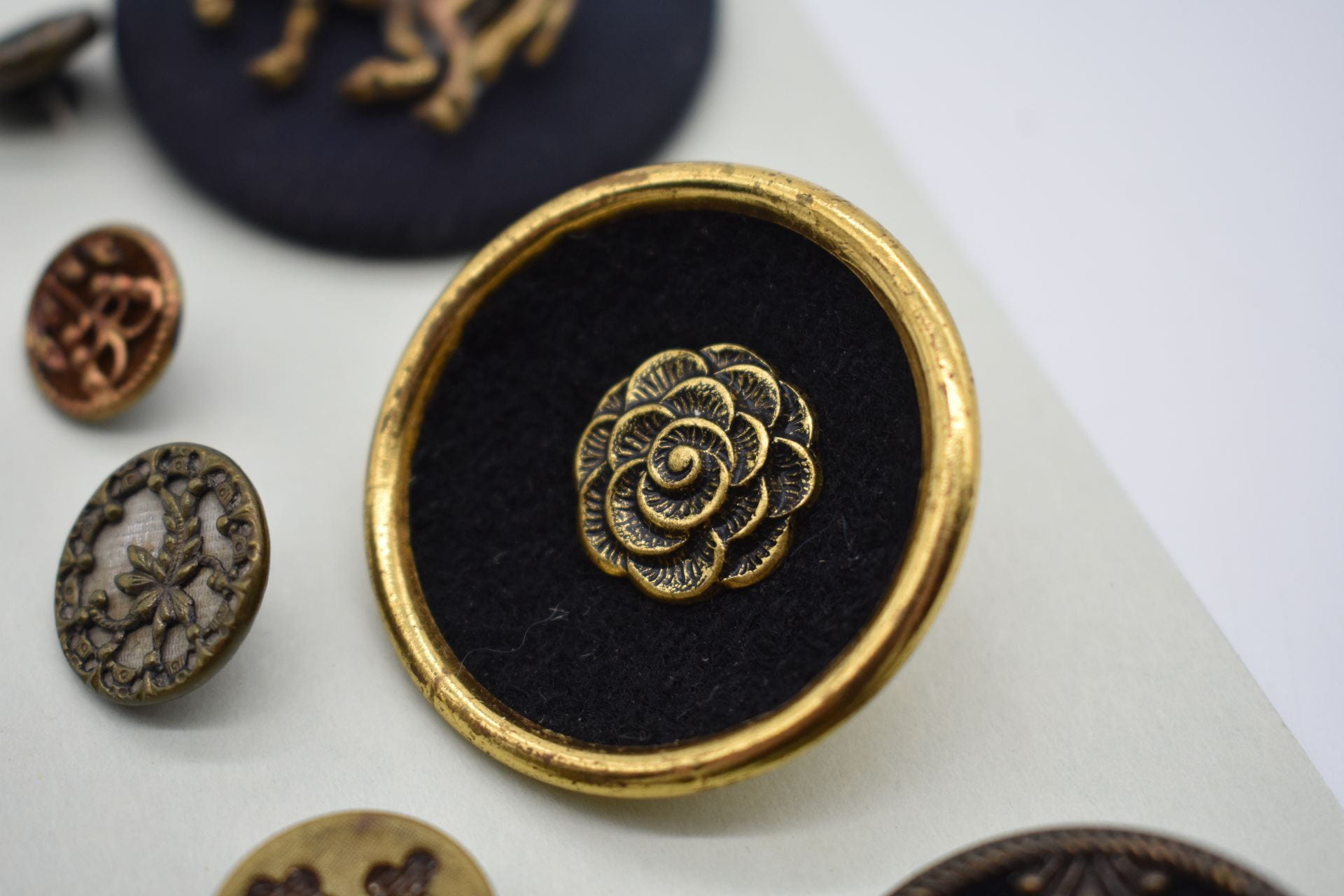 A large black and round button edged in gold with a golden flower at the center.