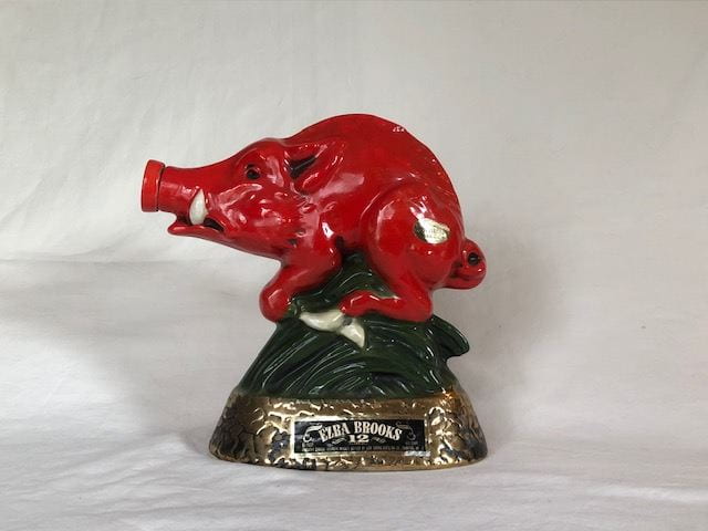 A red Razorback figurine that looks like its running with a red pedestal and the name Ezra Brooks along the bottom side.