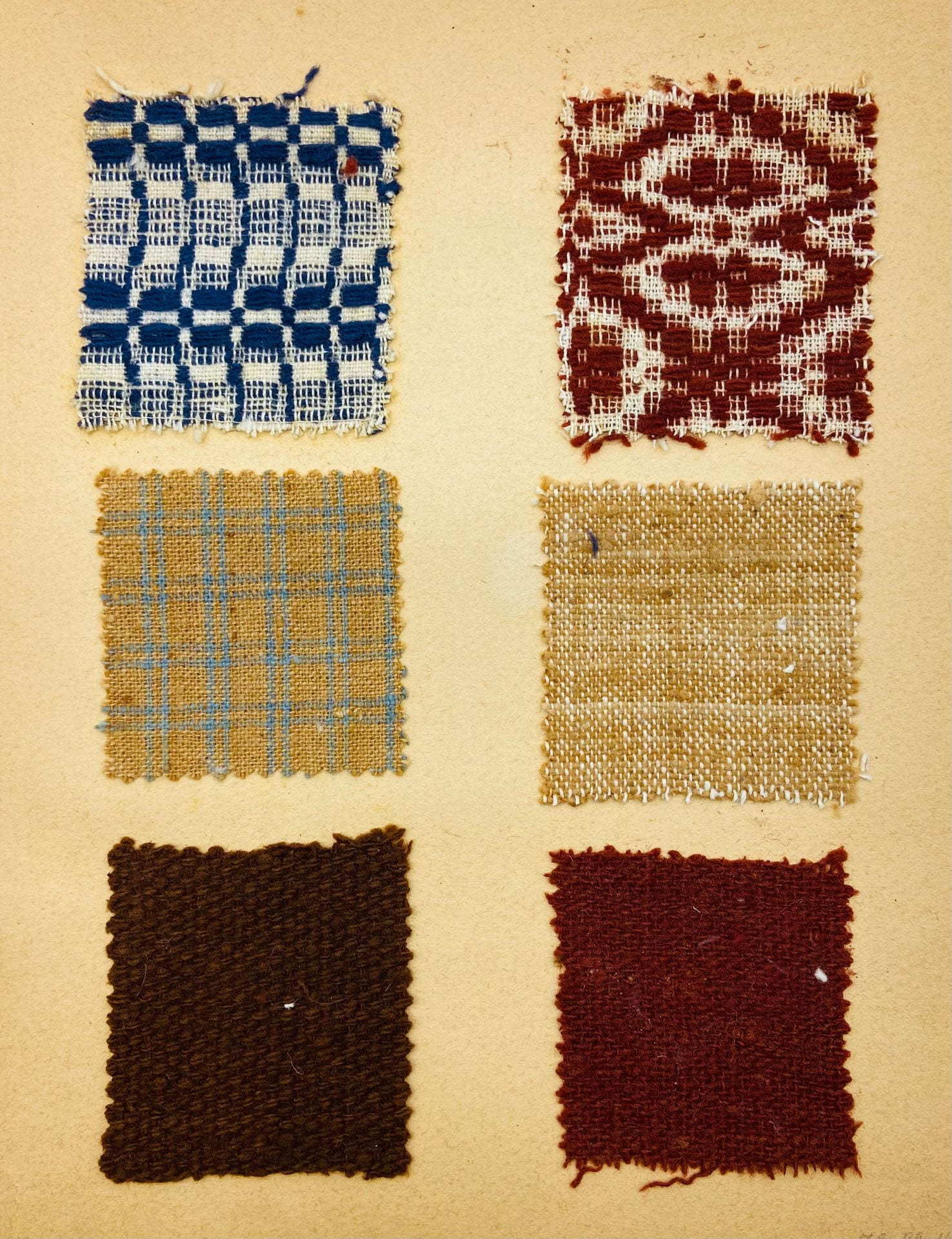 A faded page with six fabric samples cut in squares and adhered to the paper. Each is a different color, from blue and white to red and features a different pattern or weaving technique. 