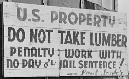 A sign in large capital letters that says "U.S. Property Do Not Take Lumber Penalty: Work with no pay or jail sentence!"