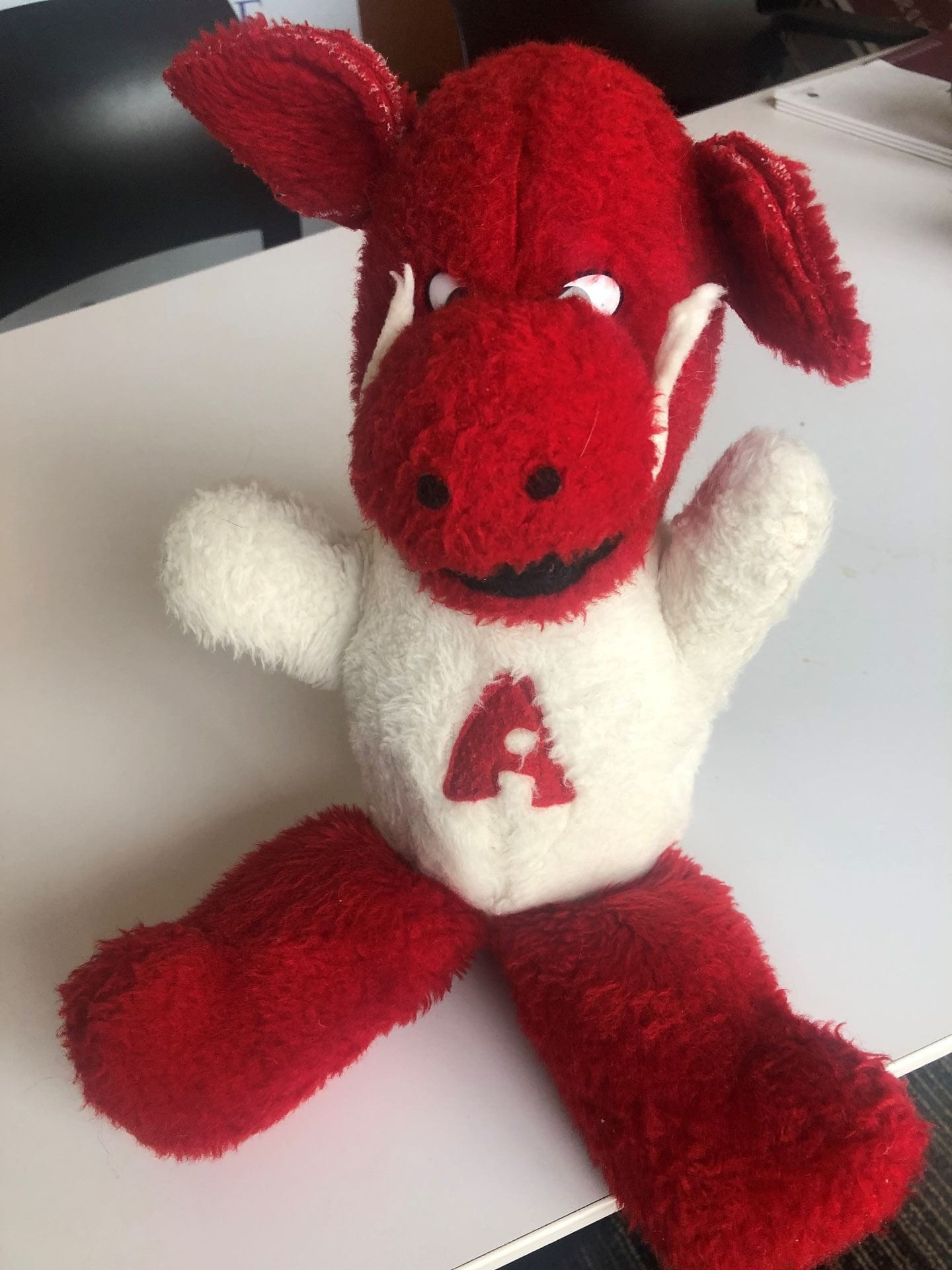 A Razorback plush with a red head and legs and white torso that has a red "A" in the center.