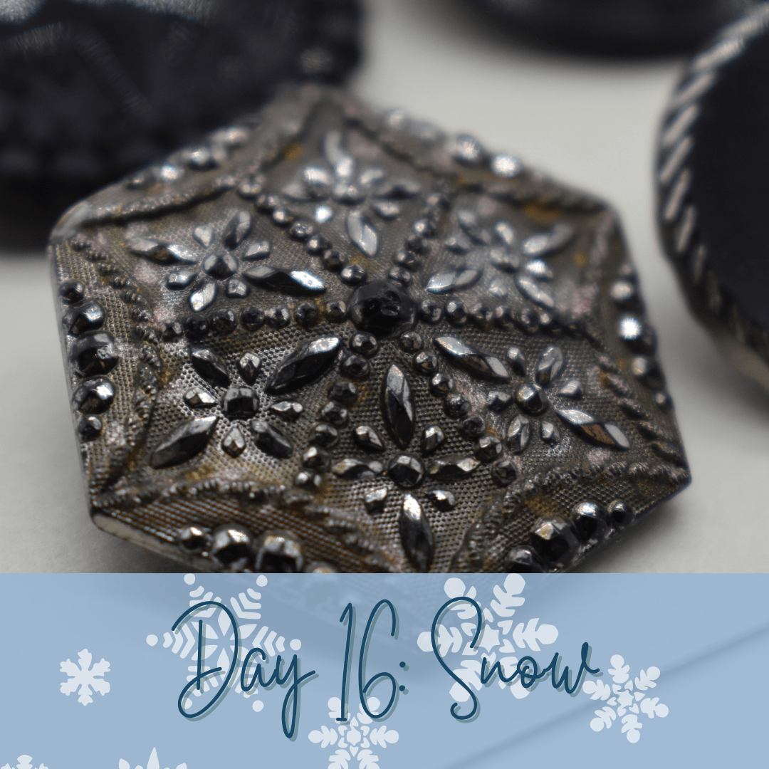 A sparkly silver button in the shape of a hexagon. A blue banner overlays at the bottom of the image with the words "Day 16: Snow."